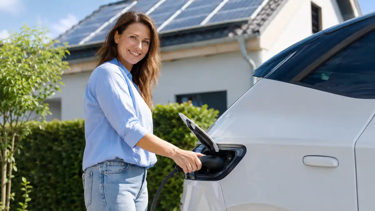 Frau lädt ein Elektroauto mit Solarstrom am eigenen Haus